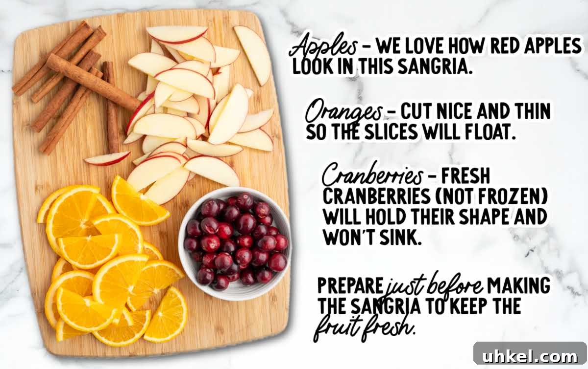 5-Minute Fireball Sangria Recipe for Quick Party Drinks 4 Cutting board with sliced red apples, orange slices, cinnamon sticks, and a bowl of cranberries prepared for Fireball sangria.