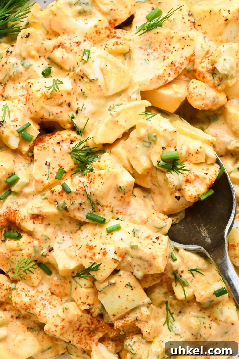 Creamy Deviled Egg Salad Recipe — Ready in 30 Minutes 13 Close up image of creamy deviled egg salad with a spoon lifting out a portion.