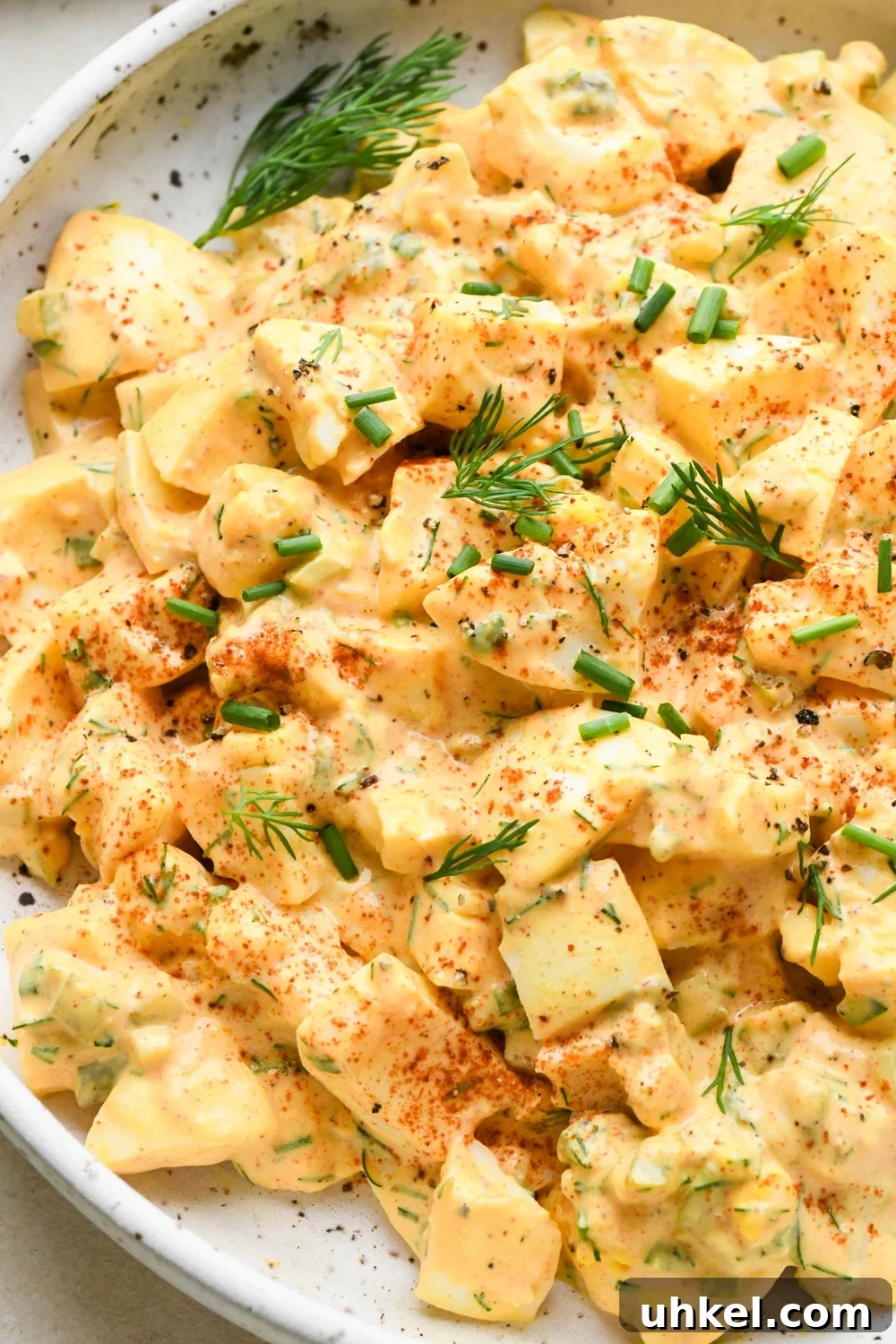 Creamy Deviled Egg Salad Recipe — Ready in 30 Minutes 3 Close up image of creamy deviled egg salad in a shallow, speckled ceramic bowl.