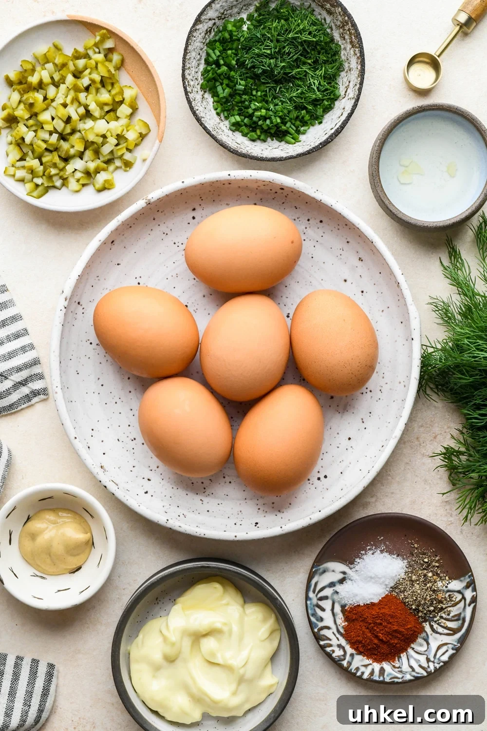 Creamy Deviled Egg Salad Recipe — Ready in 30 Minutes 4 Ingredients for deviled egg salad in various ceramics on a cream colored background.