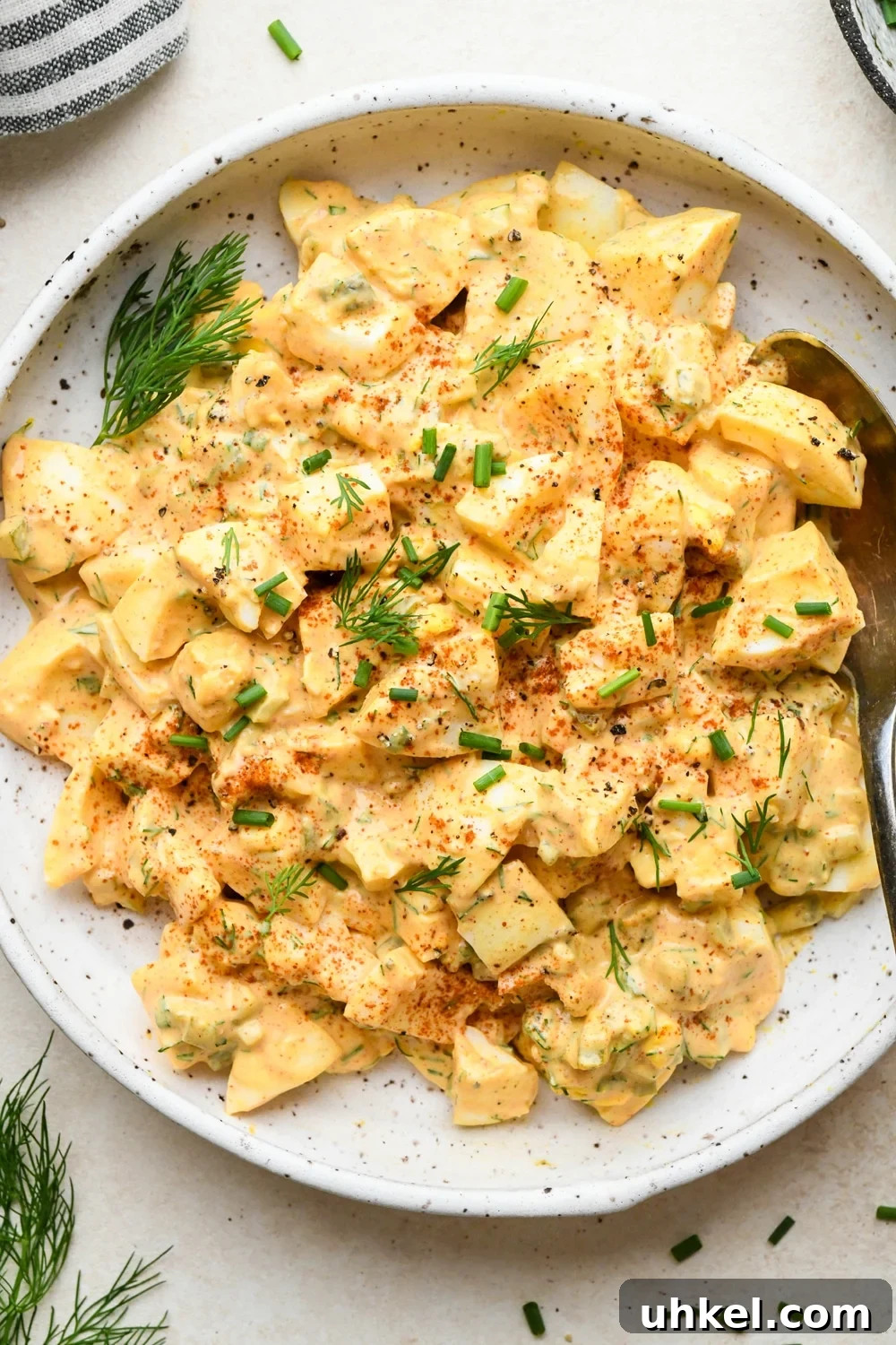 Creamy Deviled Egg Salad Recipe — Ready in 30 Minutes 5 Deviled egg salad in a shallow speckled ceramic bowl, garnished with a dash of red paprika, fresh dill, and fresh chives.