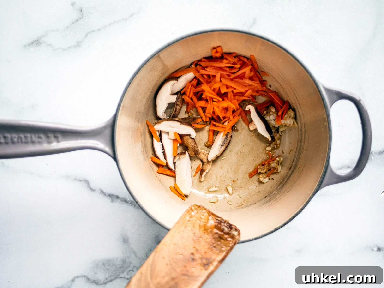 Homemade Ramen Bowl Recipe: Savory Broth & Tasty Toppings 5 Mushrooms and shredded carrots in a saucepan with garlic and ginger.
