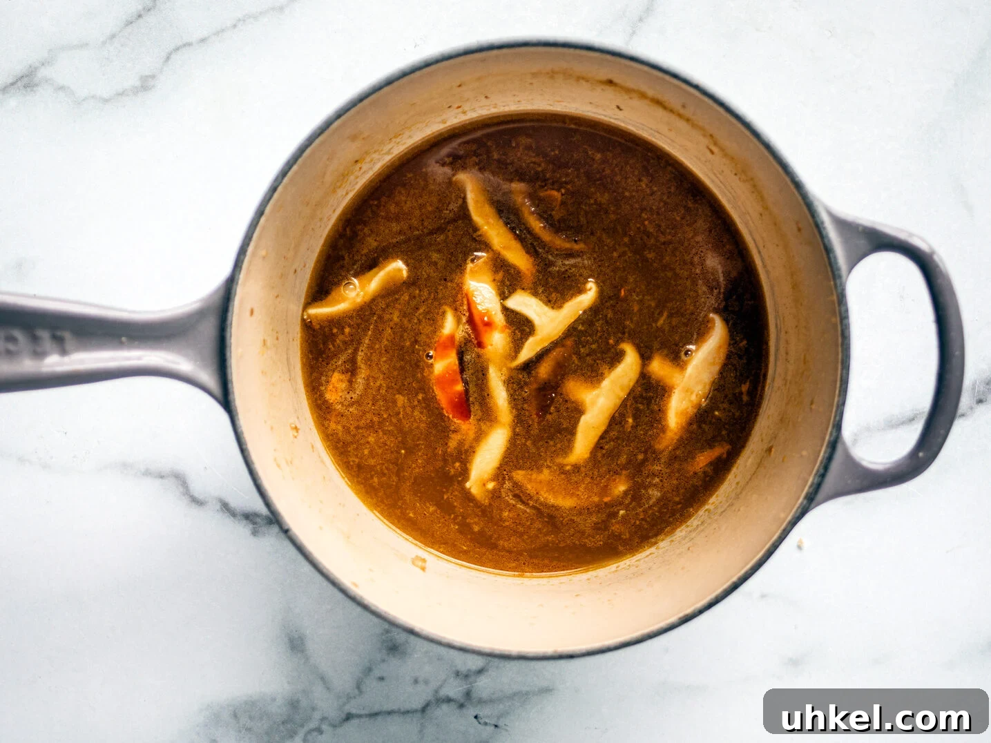 Homemade Ramen Bowl Recipe: Savory Broth & Tasty Toppings 6 Broth with mushrooms in saucepan.