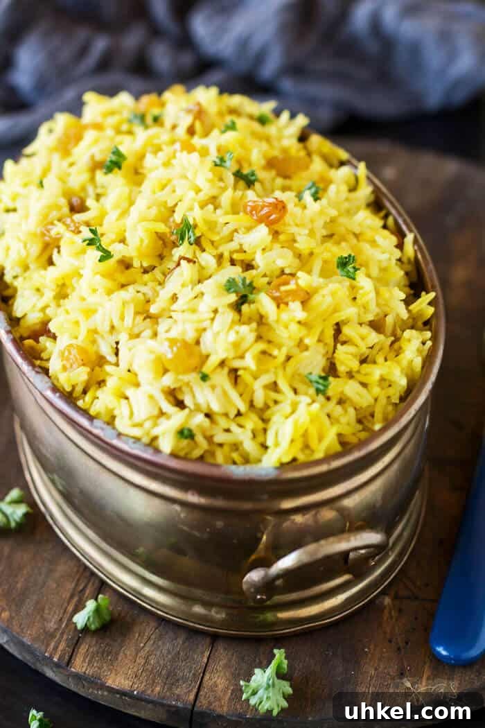 South African sultana yellow rice in an oval copper dish on a wooden trivet.