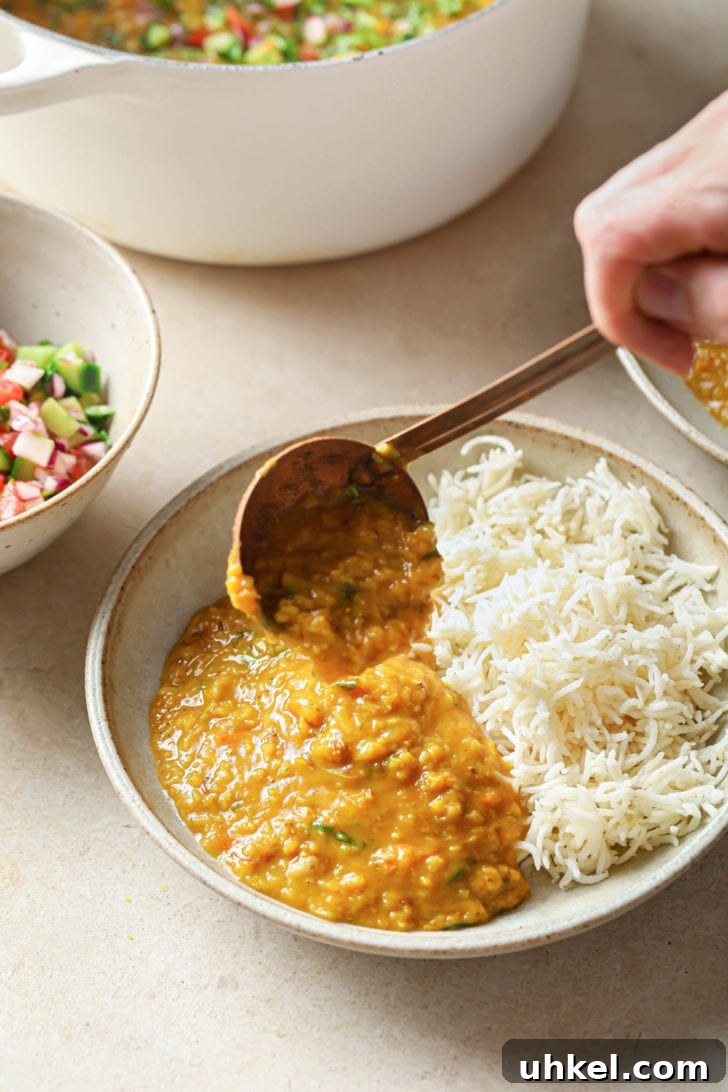 Authentic Masoor Dal (Red Lentil) Recipe for Perfect Flavor 17 Scooping Masoor dal onto a bowl with rice.