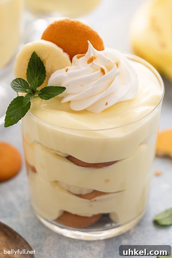 Homemade Banana Pudding Recipe with Creamy Vanilla Custard 2 close up of banana pudding in a glass, garnished with whipped cream and a mint leaf