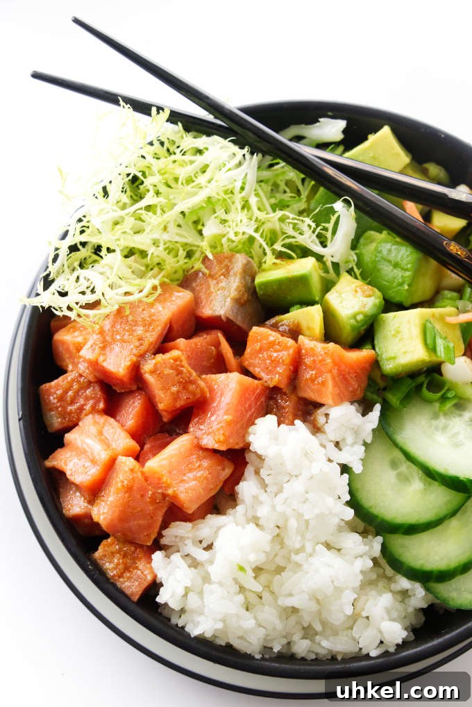 Spicy Salmon Sushi Bowl Recipe for Flavorful Weeknight Meals 2 Spicy sushi bowl with salmon, avocado, cucumber, rice, green and chopsticks.