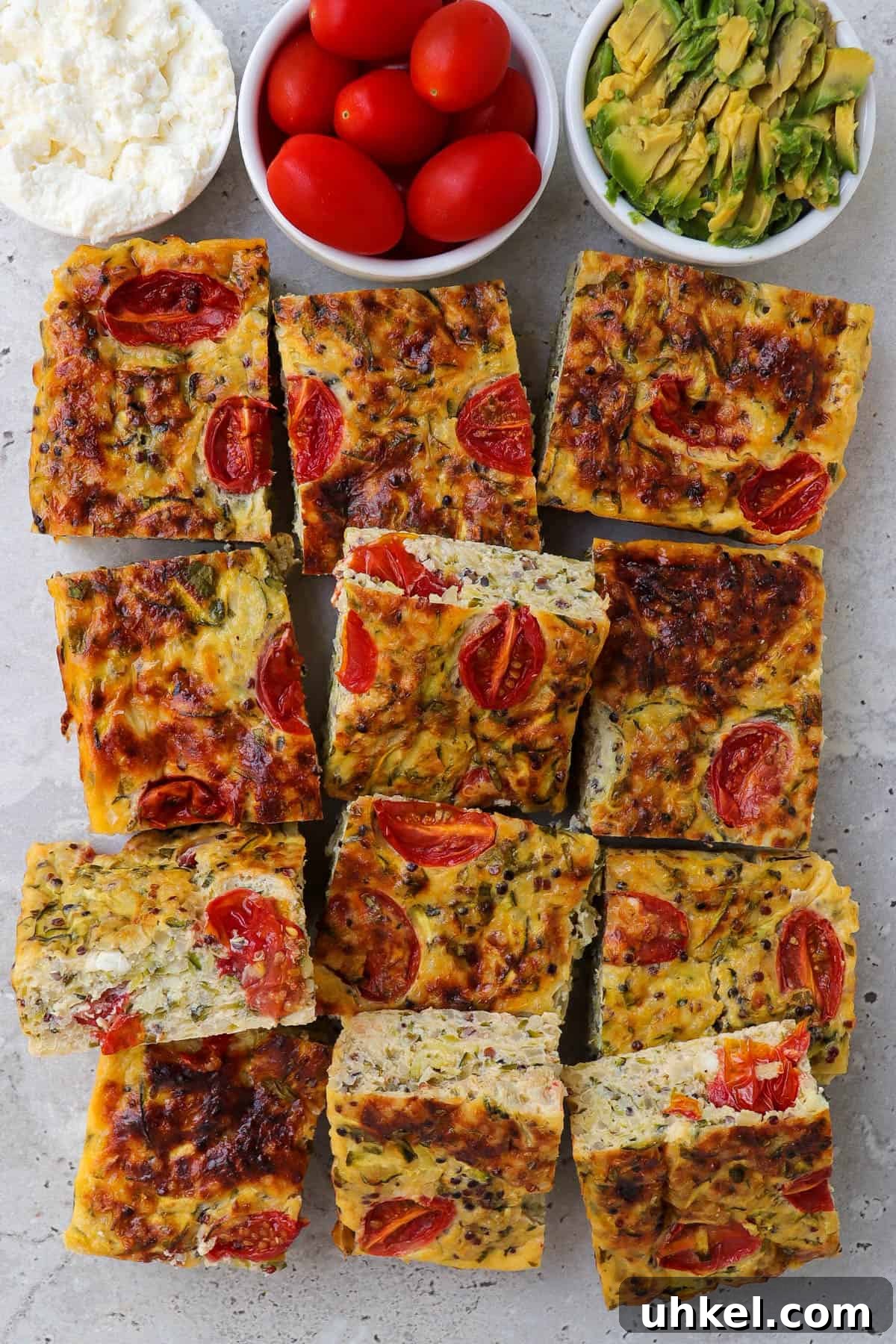 Cooked zucchini slice. Small dishes of cottage cheese, cherry tomatoes and mashed avocado on the top side for decoration.