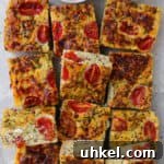 Cooked zucchini slice. Small dishes of cottage cheese, cherry tomatoes and mashed avocado on the top side for decoration.