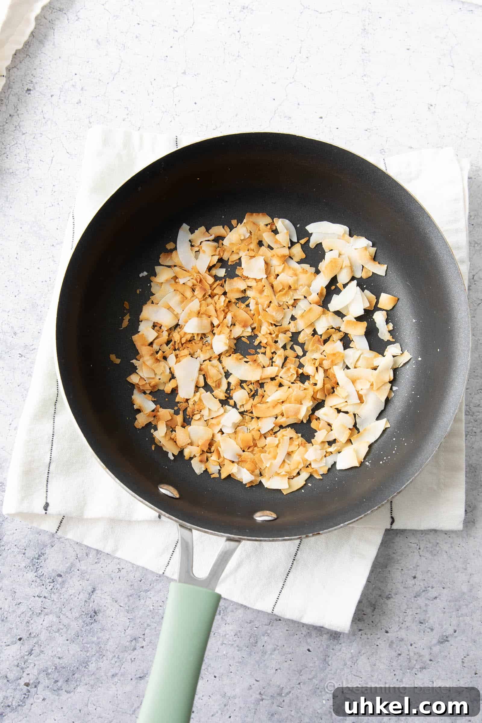 How to Toast Coconut Perfectly: Quick Oven and Stovetop Methods 2 Cooling Toasted Coconut in Pan on a kitchen towel