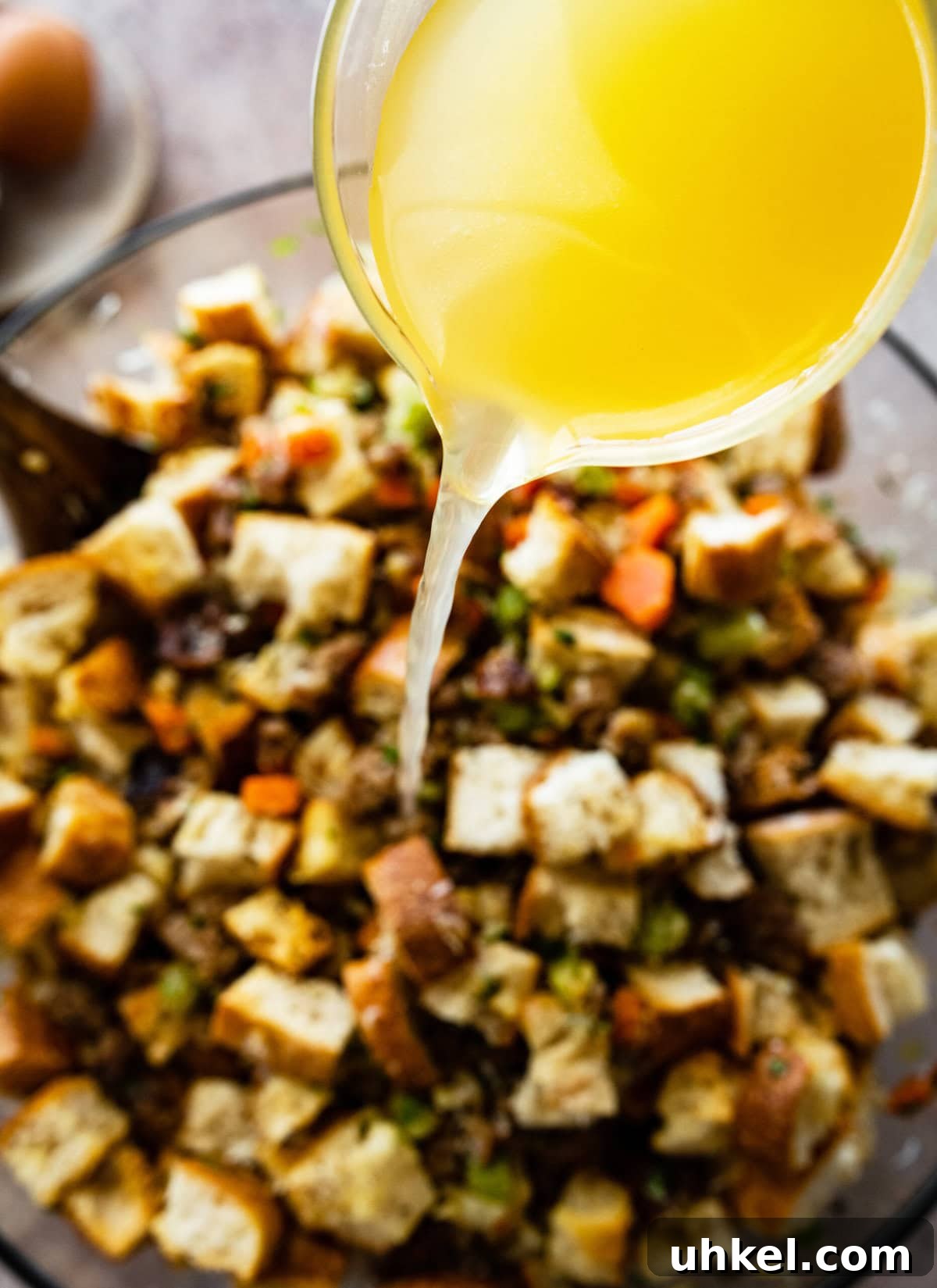 Sausage and Chestnut Ciabatta Stuffing Recipe for Holiday Tables 12 Adding broth to the bowl.