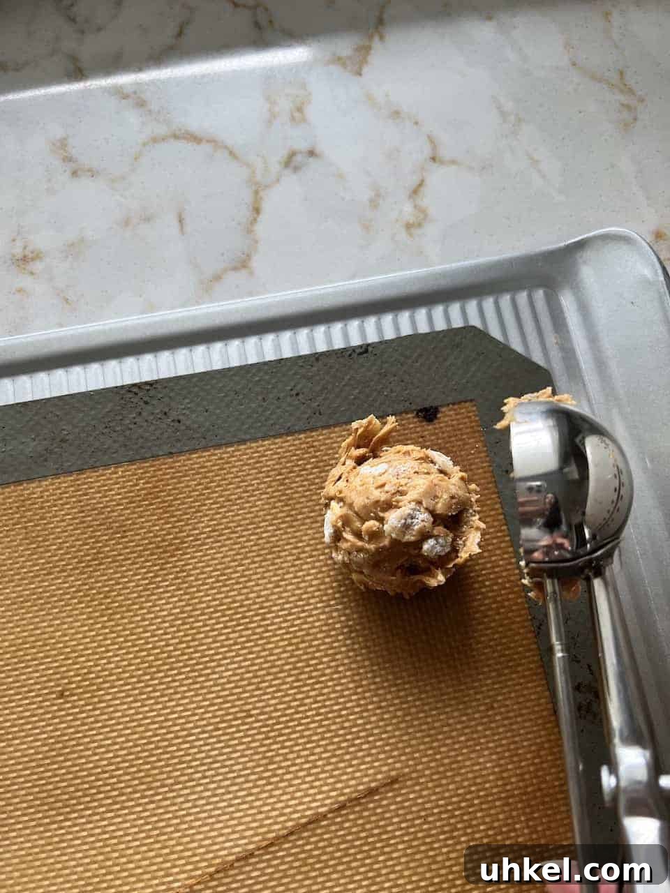 Vegan No-Bake Chocolate Peanut Butter Krispie Balls 6 process of putting a scoop of Peanut Butter Bon Bon on a silicone mat