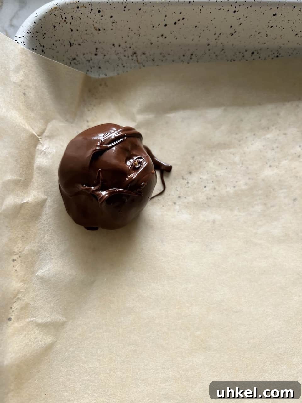 Vegan No-Bake Chocolate Peanut Butter Krispie Balls 8 process of placing a chocolate covered bon bon on parchment paper