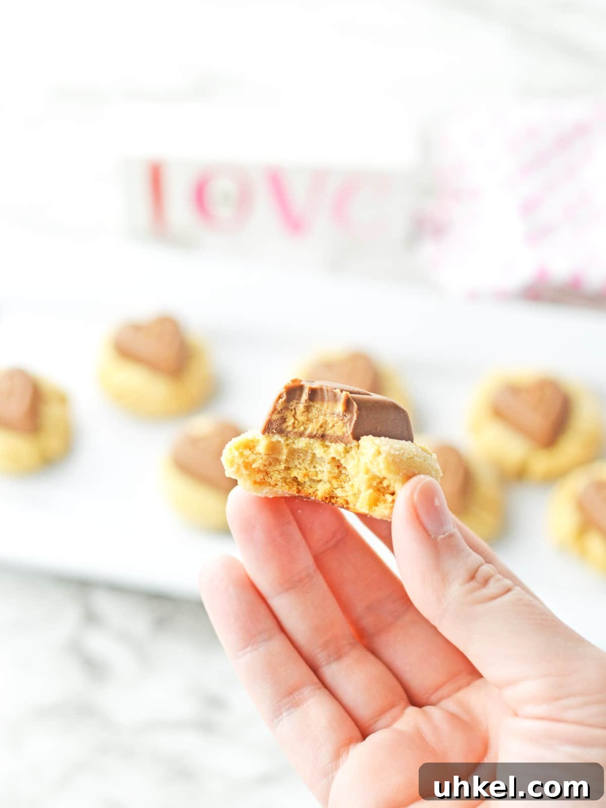 Peanut Butter Blossom Cookies for a Valentine’s Day Treat 7 hand holding a cookie with a bite taken out