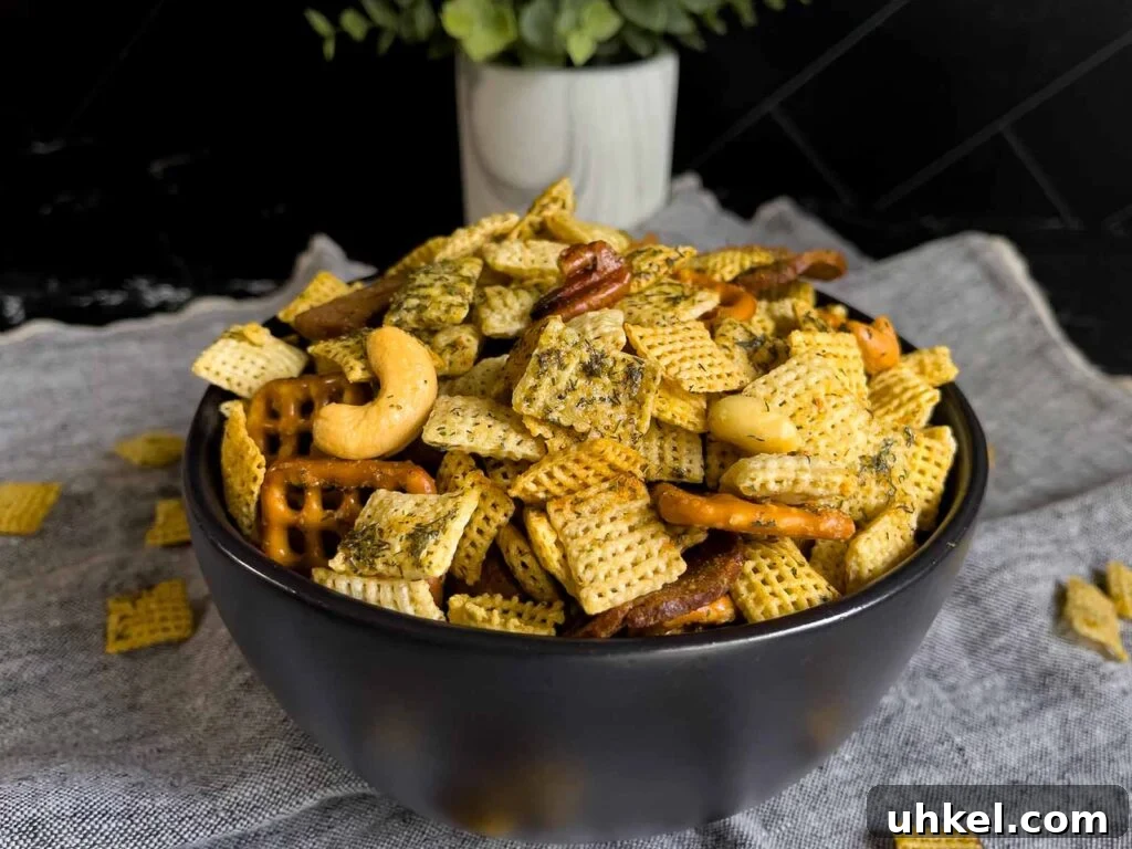 Tangy Dill Pickle Chex Mix Snack Recipe for Parties 2 Dill Pickle Chex Mix in a small dark bowl on a light linen napkin.