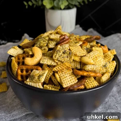 Tangy Dill Pickle Chex Mix Snack Recipe for Parties 12 Dill Pickle Chex Mix in a small dark bowl on a light linen napkin.