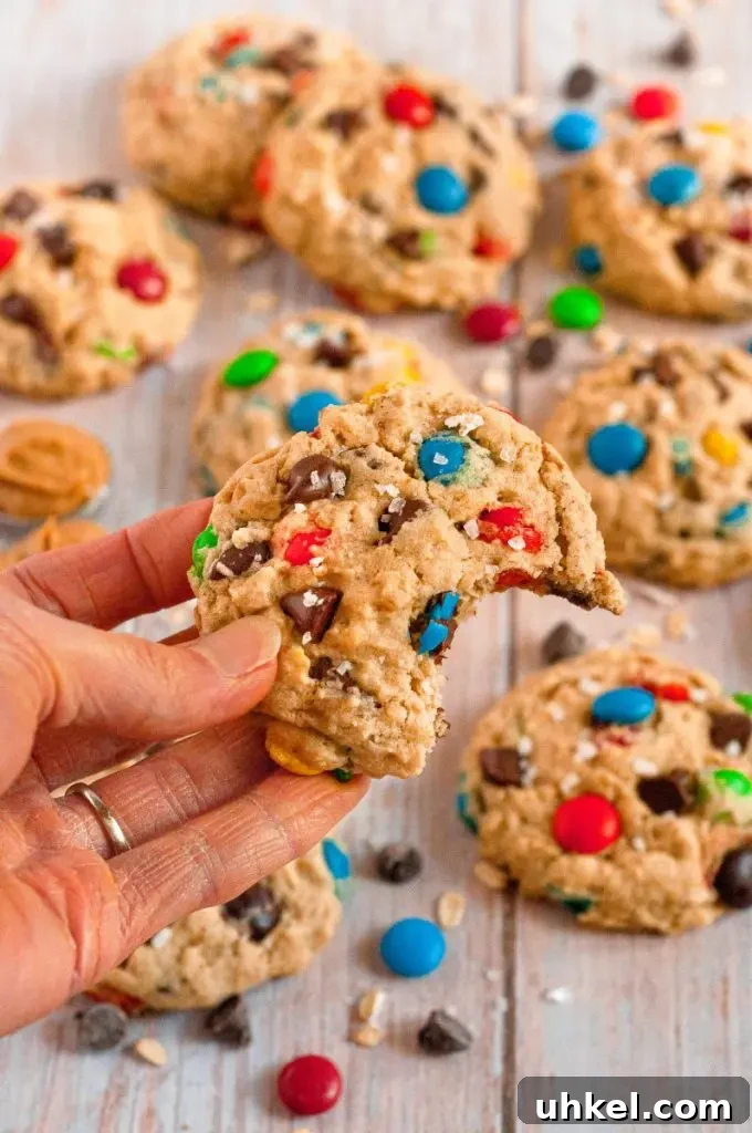 Light golden brown monster cookies full of chocolate chips and brightly colored M&M style chocolate candies.