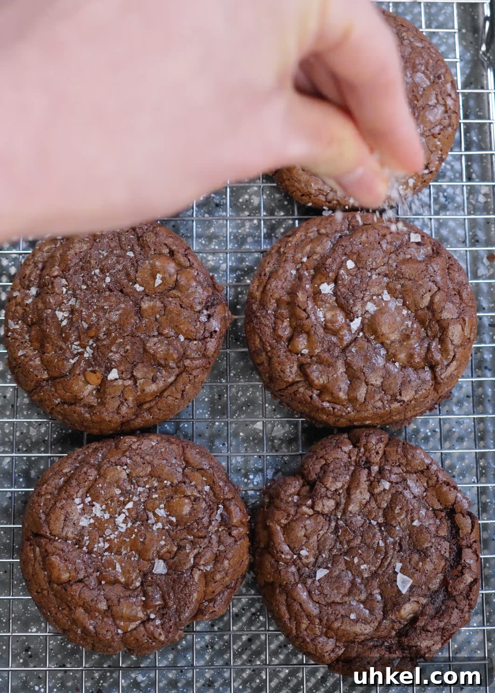 Flaky sea salt sprinkled over warm brownie cookies to enhance chocolate flavor and balance sweetness.