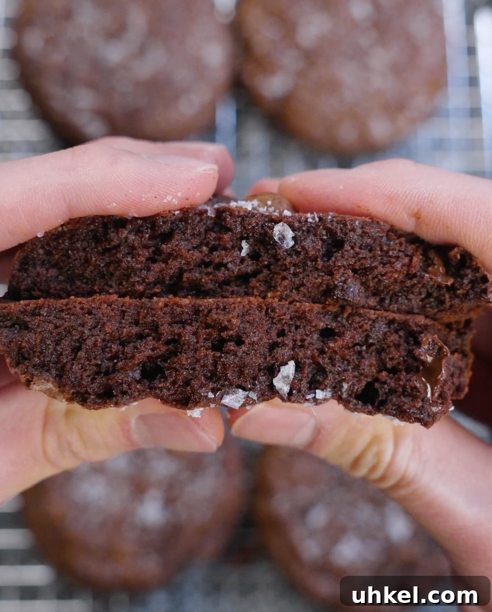 Brownie cookie split in half to show a rich, moist, fudgy interior with deep chocolate crumb and melted chocolate throughout.