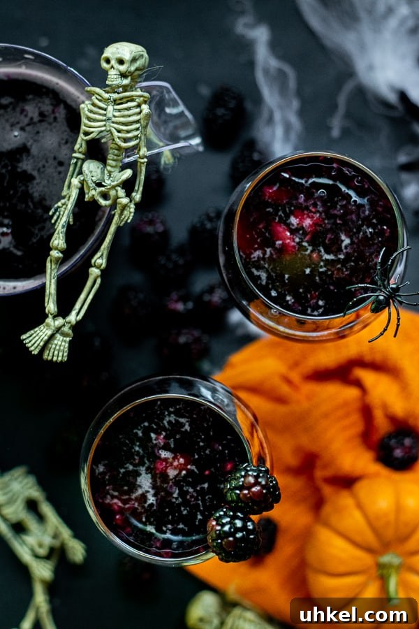wine glasses full of black fruit and halloween sangria on a black table