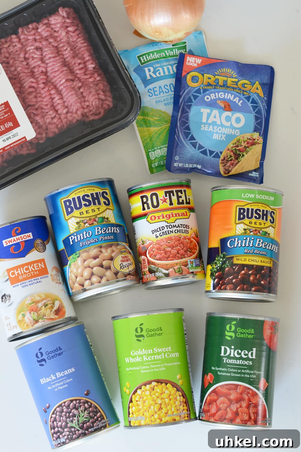 Hearty 7-Can Taco Soup Recipe for Quick Weeknight Dinners 4 Ingredients for taco soup including ground beef, onion, ranch dressing seasoning, taco seasoning and 7 cans.