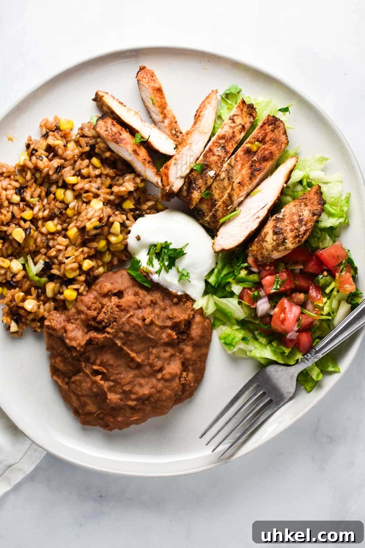 Juicy Mexican-Style Grilled Chicken with Zesty Marinade 2 A plate of grilled chicken on top of lettuce and tomatoes.