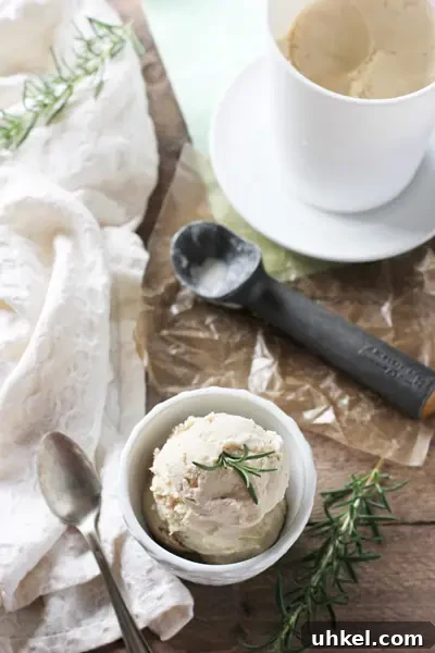 Recipe for dreamy, creamy rosemary ice cream! A sweet vanilla ice cream base infused with just the right amount of fresh rosemary! Homemade Rosemary Ice Cream in a white bowl with a pint to the side.