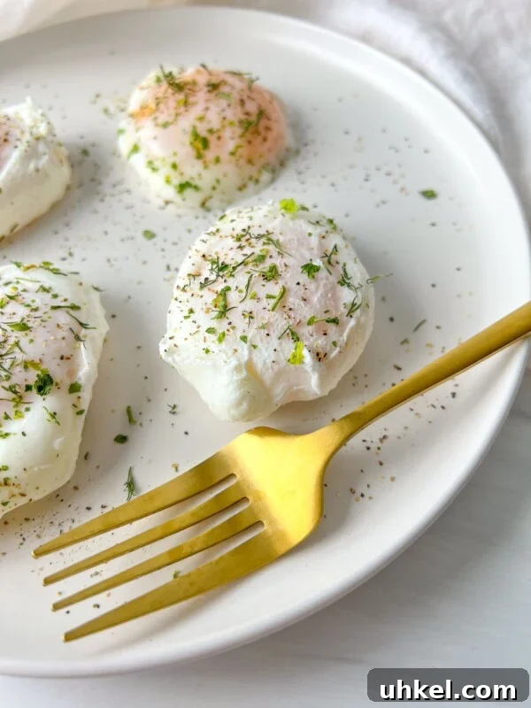 A white plate with three poached eggs sprinkled with herbs and black pepper.