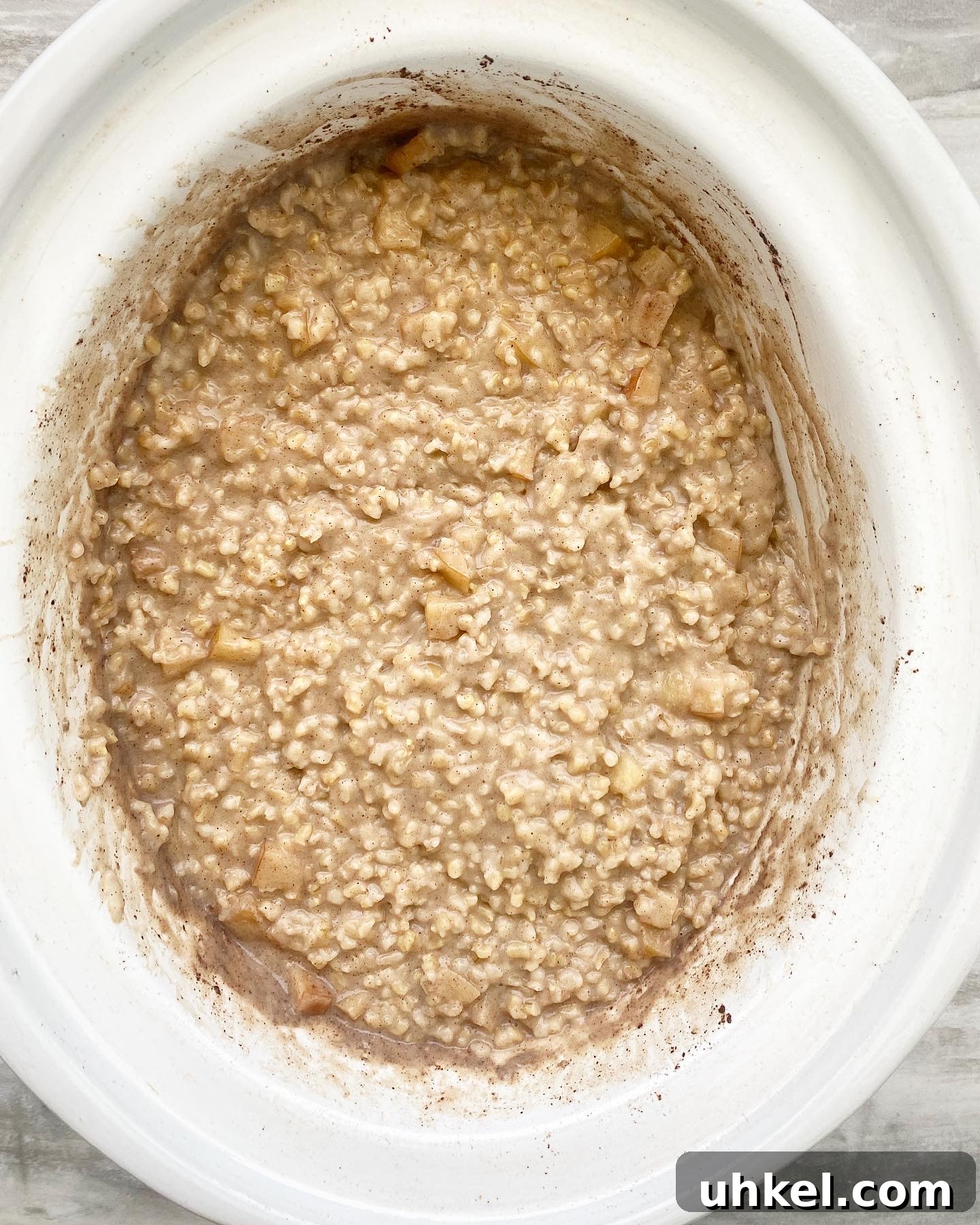 overhead shot of cooked apple cinnamon oatmeal in a white slow cooker