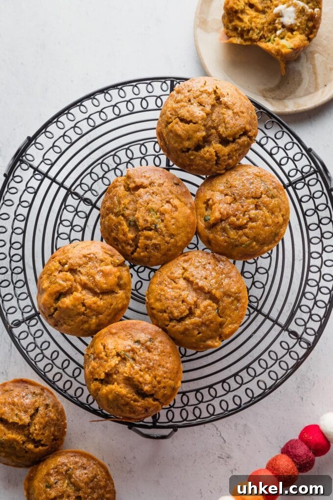 Moist Pumpkin Zucchini Muffins with Warm Spices 11 Batch of pumpkin zucchini muffins cooling on a countertop.