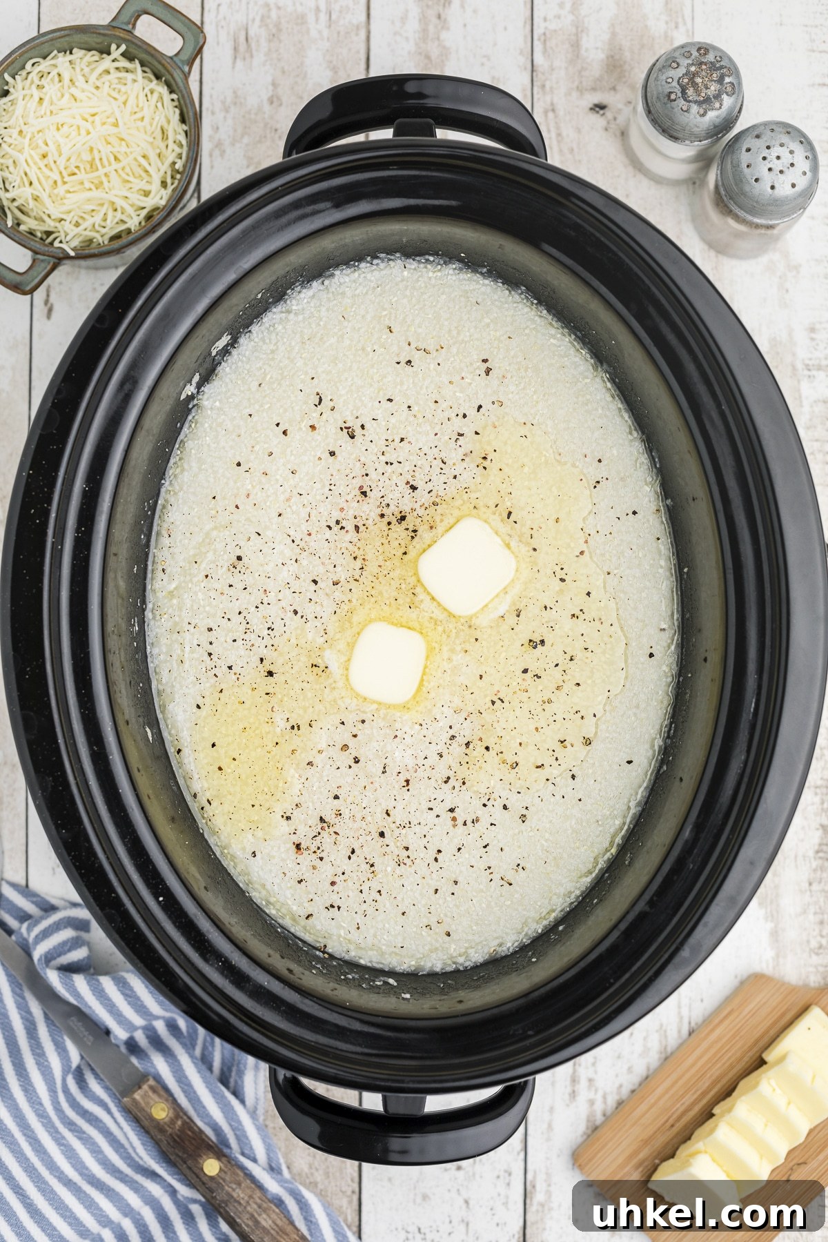 Slow-Cooker Creamy Grits Recipe for Perfectly Smooth Breakfast 2 overhead shot of grits with pepper and butter on top.