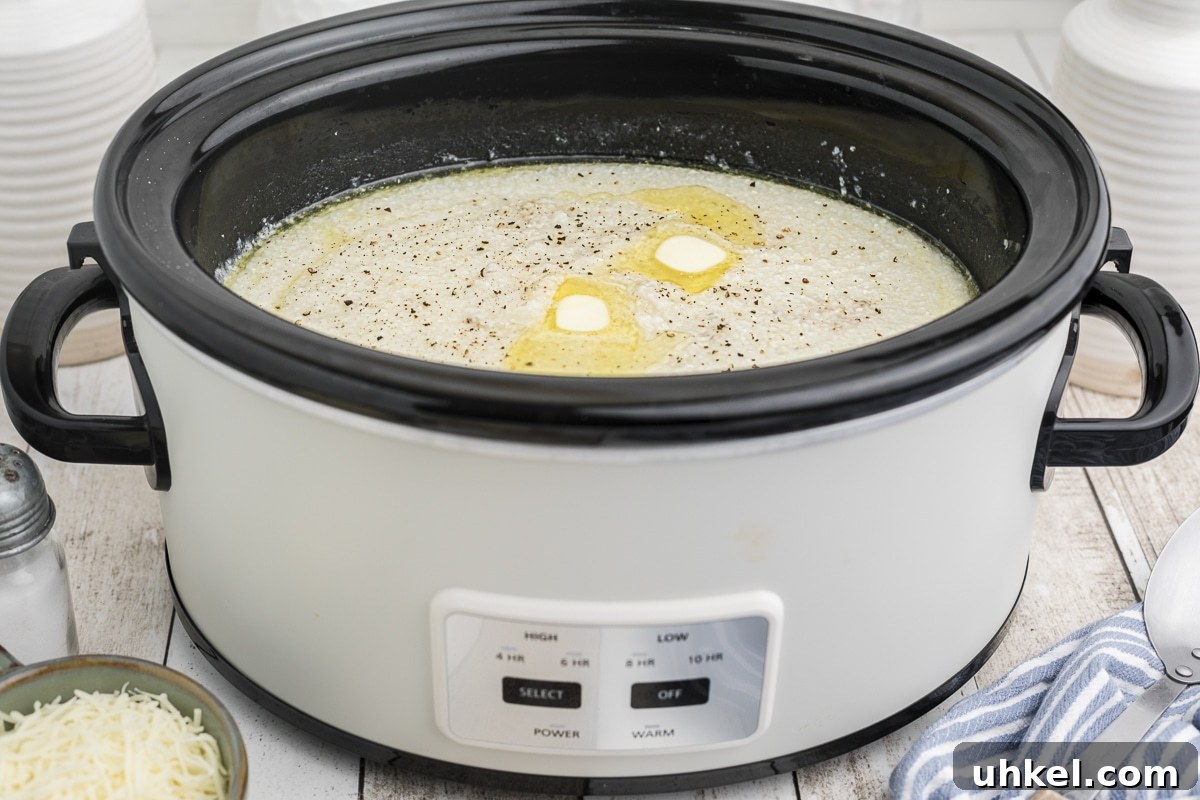 Slow-Cooker Creamy Grits Recipe for Perfectly Smooth Breakfast 5 side view of grits in the crockpot with butter on top.