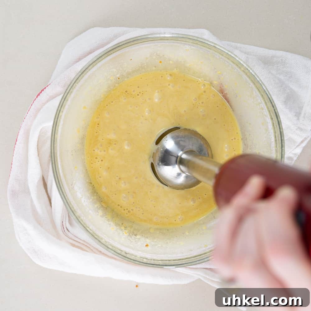 Authentic Caesar Salad Recipe with Creamy Homemade Dressing 4 immersion blender mixing egg yolks in a glass bowl