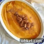 whipped sweet potatoes in casserole dish topped with pumpkin pie spice, pecans and a little maple syrup