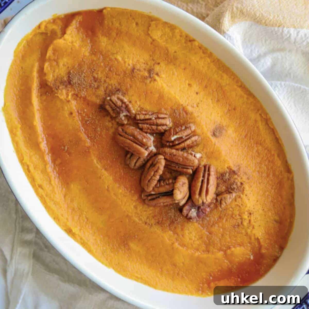 Creamy Whipped Sweet Potatoes Recipe for Holiday Sides 8 Whipped sweet potatoes topped with maple syrup and pecans in casserole dish.
