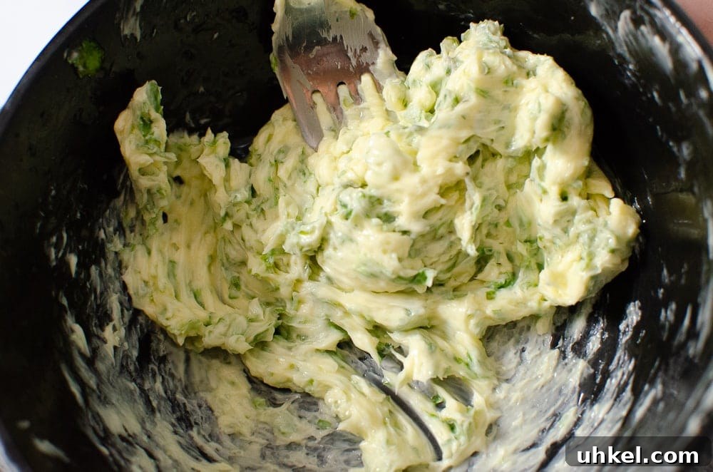 Crab Tagliatelle with Shredded Crab and Lemon Herb Sauce 5 Butter and chopped parsley being mixed together in a black bowl with a silver fork