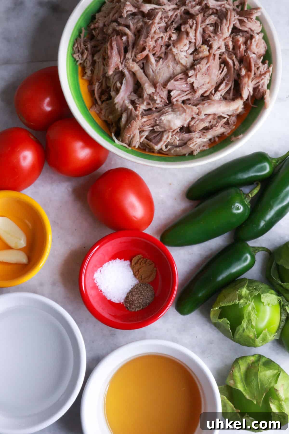 Salsa Verde Pulled Pork Sandwiches with Tangy Cilantro Sauce 3 Bowl of shredded pork, some tomatoes, jalapeños, tomatillos, a bowl with garlic cloves, another with chicken broth, another with water, and another with spices.