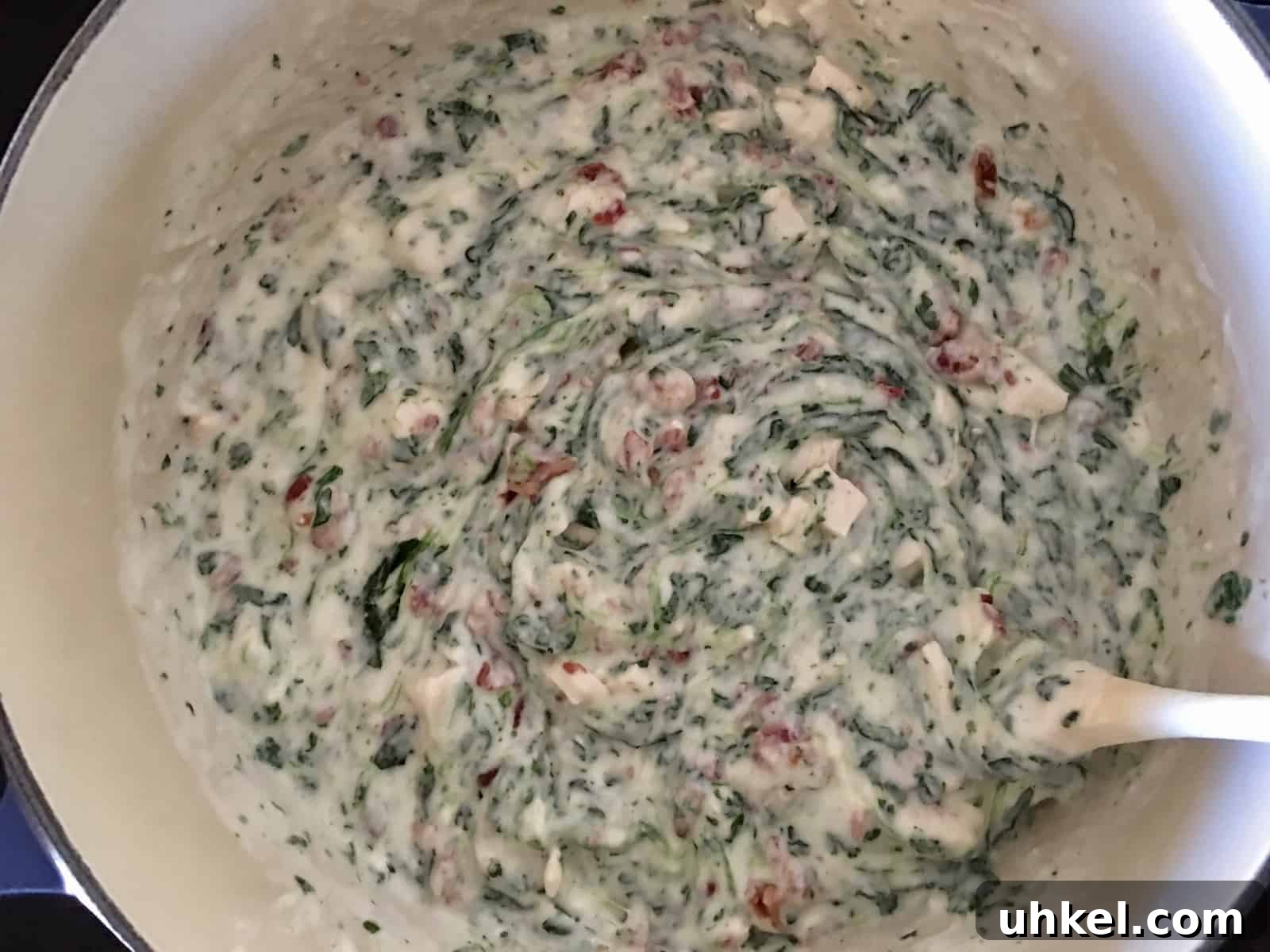 Creamy Chicken, Bacon & Spinach Tortellini Bake Recipe 6 dutch oven on stove top with Alfredo sauce, spinach, bacon, and chicken stirred in.