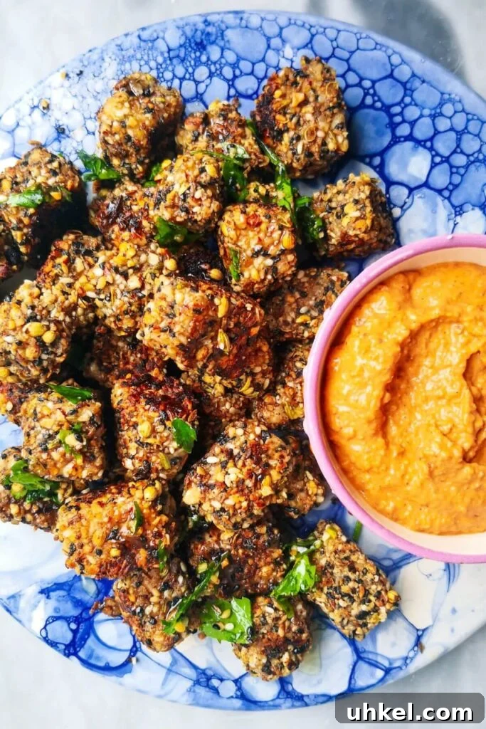 Halloumi bites on a blue marble plate with red pepper sauce on the side.