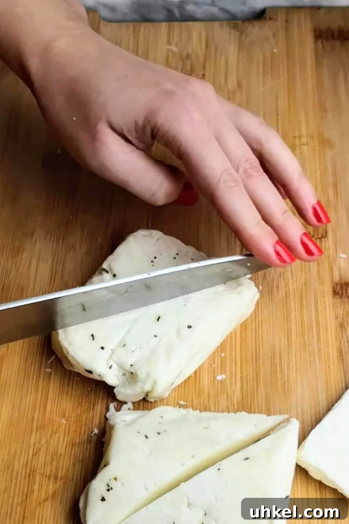 Hand cutting large triangle of halloumi with a knife.
