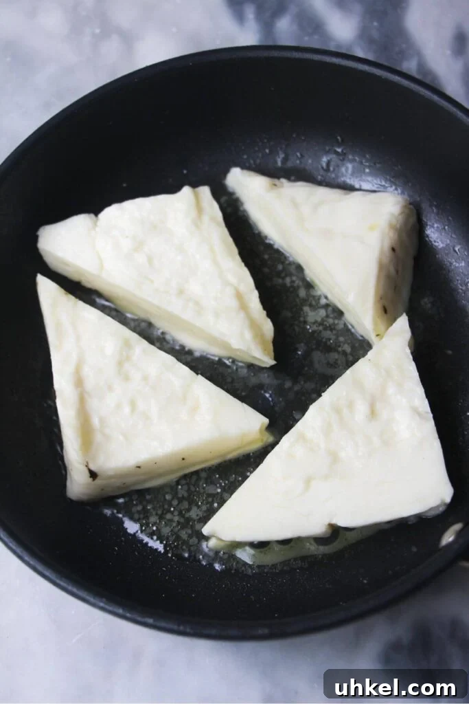 4 wedges of halloumi in a small black pan.