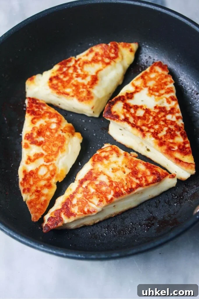 4 wedges of golden pan fried halloumi in a small black pan.