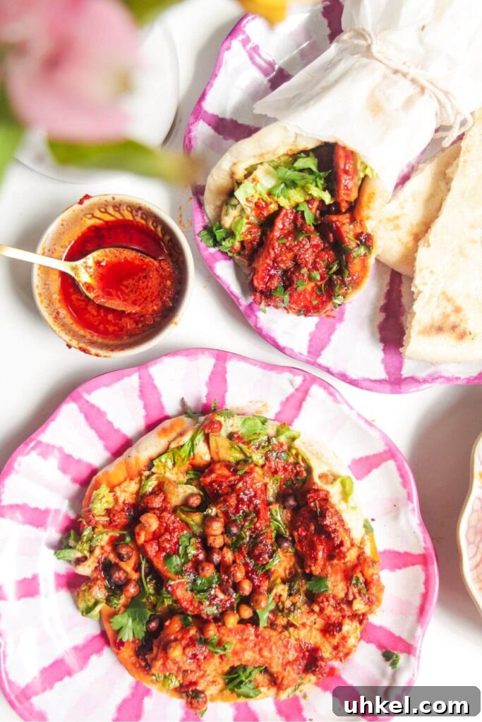 Two flatbreads with honey harissa halloumi, hummus and chickpeas on top.
