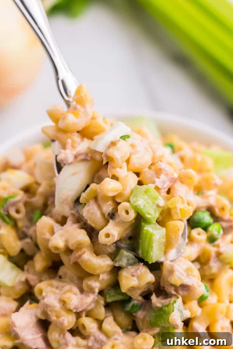 Creamy Tuna Macaroni Salad Recipe for Picnics & Potlucks 11 serving the Tuna Macaroni Salad with a metal spoon.
