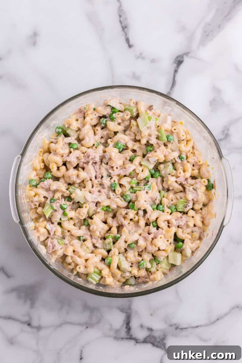 Creamy Tuna Macaroni Salad Recipe for Picnics & Potlucks 7 macaroni salad mixed with the dressing in large glass bowl.