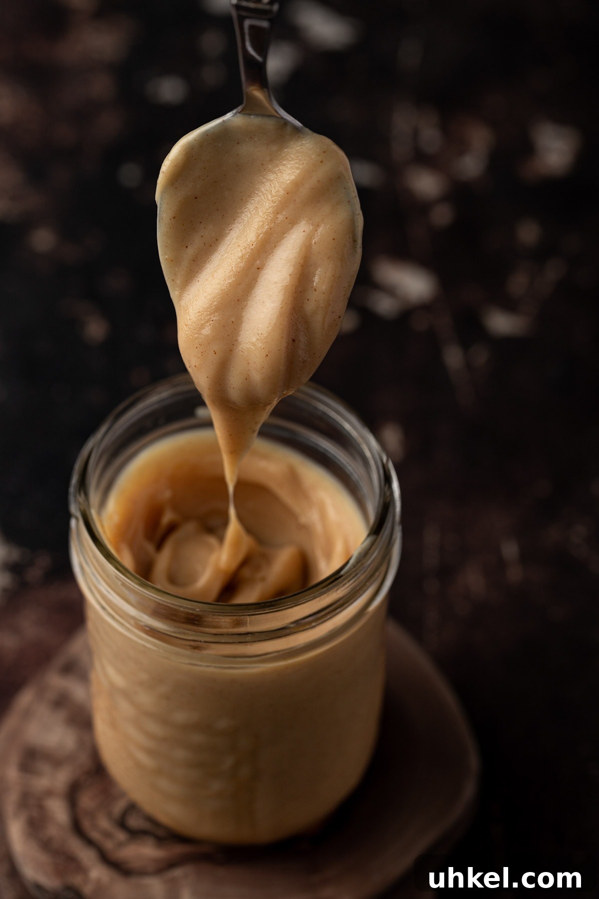 Decadent Peanut Butter Ganache Recipe for Cakes and Desserts 2 A spoonful of peanut butter ganache dripping down into a mason jar.