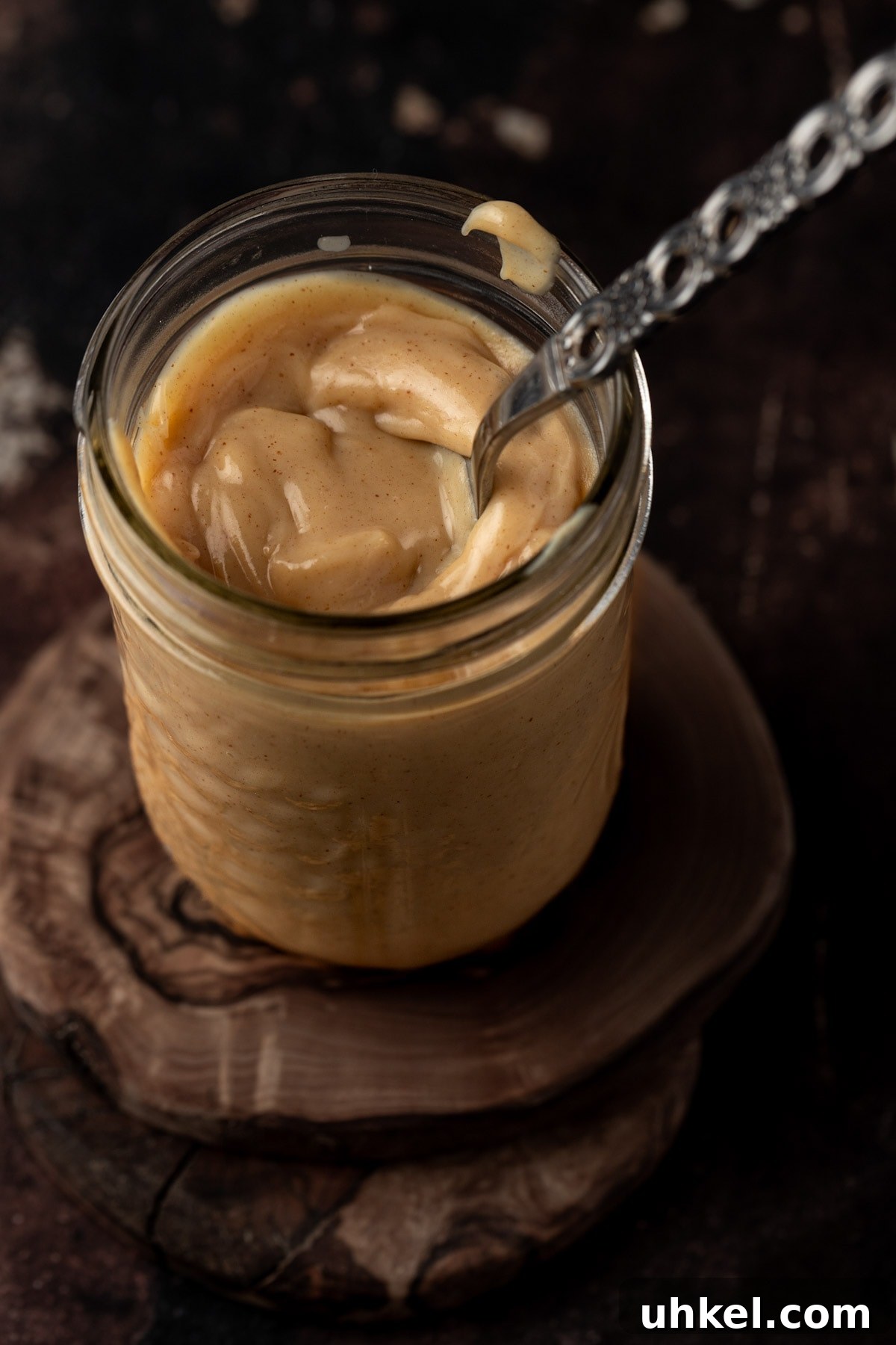 Decadent Peanut Butter Ganache Recipe for Cakes and Desserts 8 A mason jar filled with peanut butter ganache, on a wooden table.