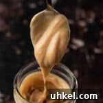 A spoonful of peanut butter ganache dripping down into a mason jar.