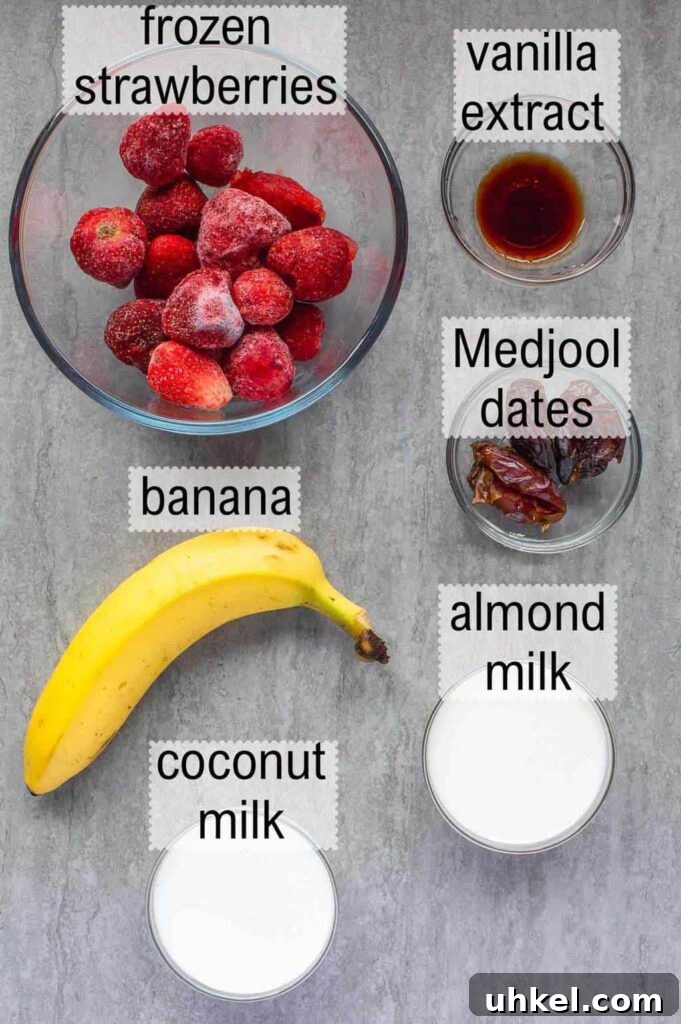Creamy Strawberry Banana Vegan Smoothie Recipe 3 Top down view of six ingredients, frozen strawberries, vanilla extract, banana, coconut milk, almond milk and medjool dates on a grey background.
