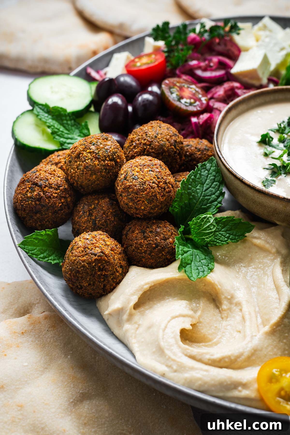 Crispy Authentic Middle Eastern Falafel Recipe 12 A falafel plate with crispy Israeli falafel, creamy hummus, tahini sauce, pita bread and fresh salad.